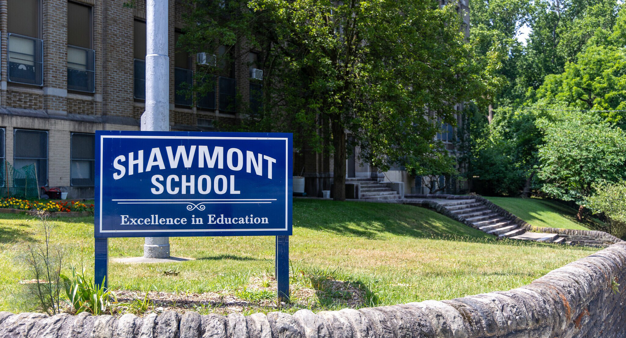 Shawmont School sign in front of the school building and tree-lined grounds.